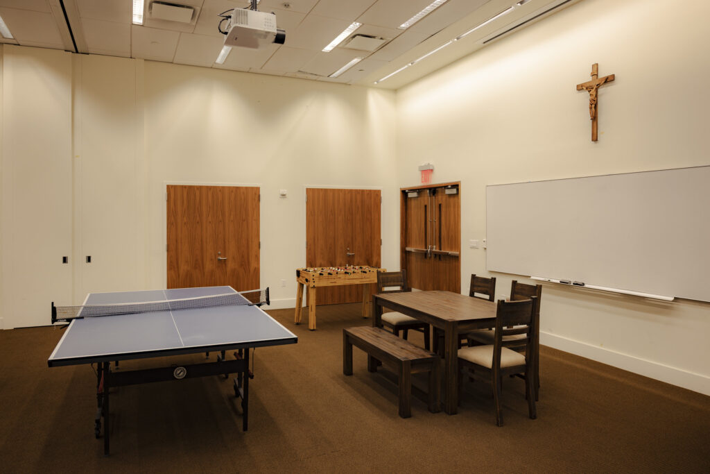 Game room with ping pong, foosball, and a table with chairs at The Catholic Center at NYU